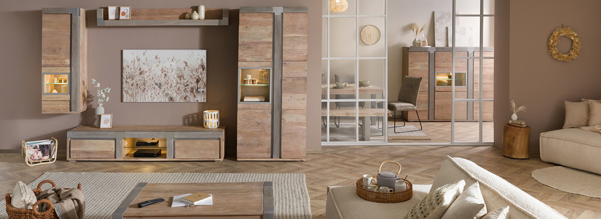 Moderne woon- en eetkamer uit de serie AMSTERDAM met wandmeubel, vitrinekasten, salontafel en open boekenkast in lichte houtlook en een crèmekleurige bank