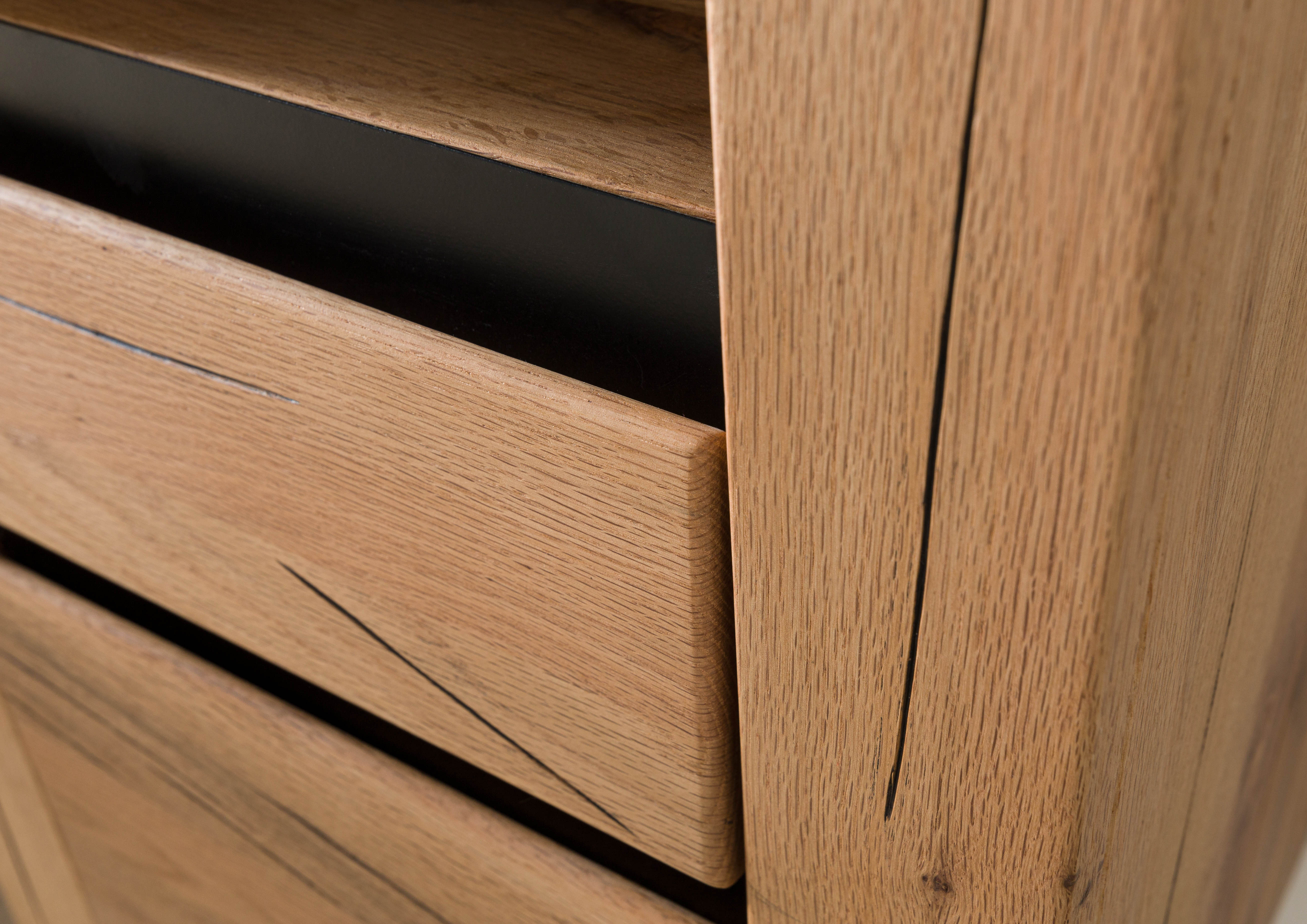 Detailfoto van de hoge kast MONTREUX van massief wild eiken met scheurstructuur en zwarte metalen sierlijsten.