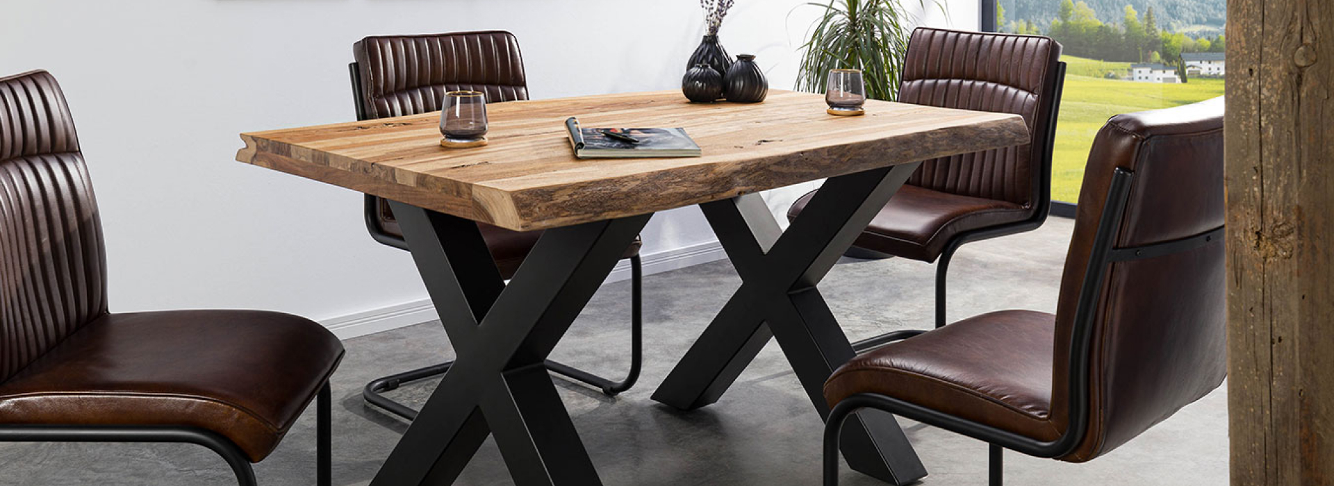 Grote boomtafel met massief houten blad, antracietmatte X-poten en stijlvol gedekte eettafel.