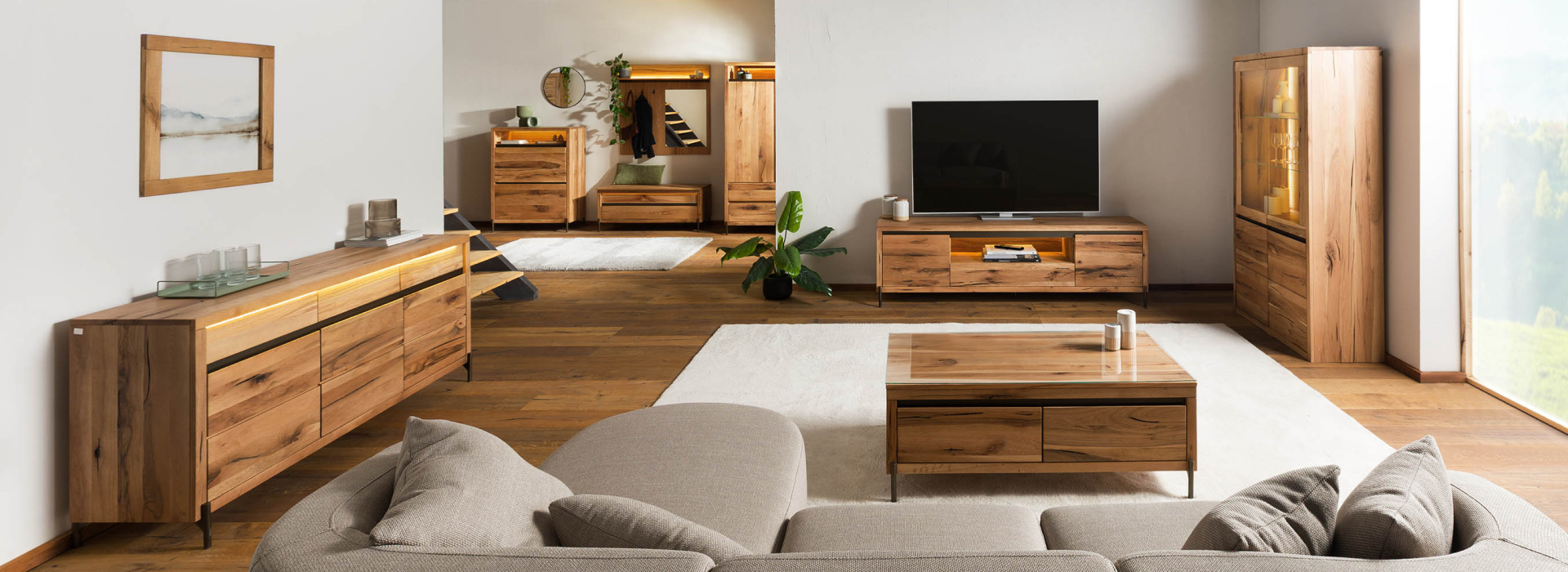 Lichte woonkamer met massief houten meubels, dressoir, tv-kast, salontafel en vitrinekast met sfeervolle verlichting.