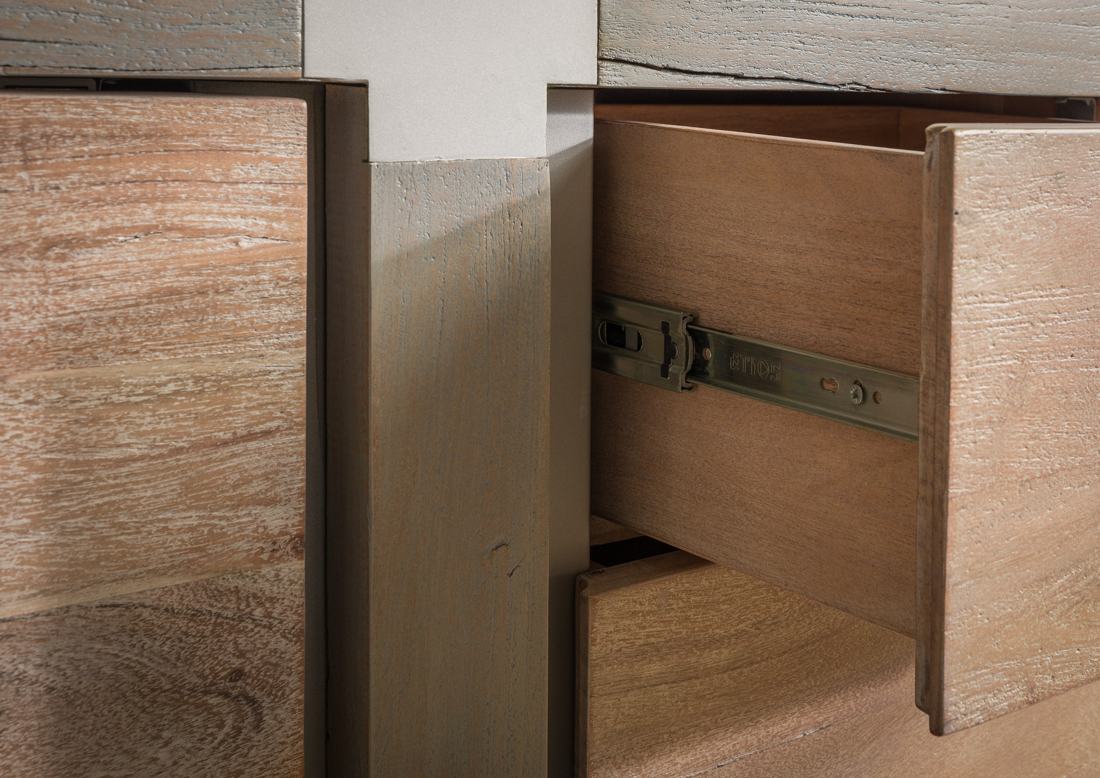 Detailopname van een gedeeltelijk geopende houten lade met zichtbare metalen geleiderail in een dressoir met grijsbeige accenten