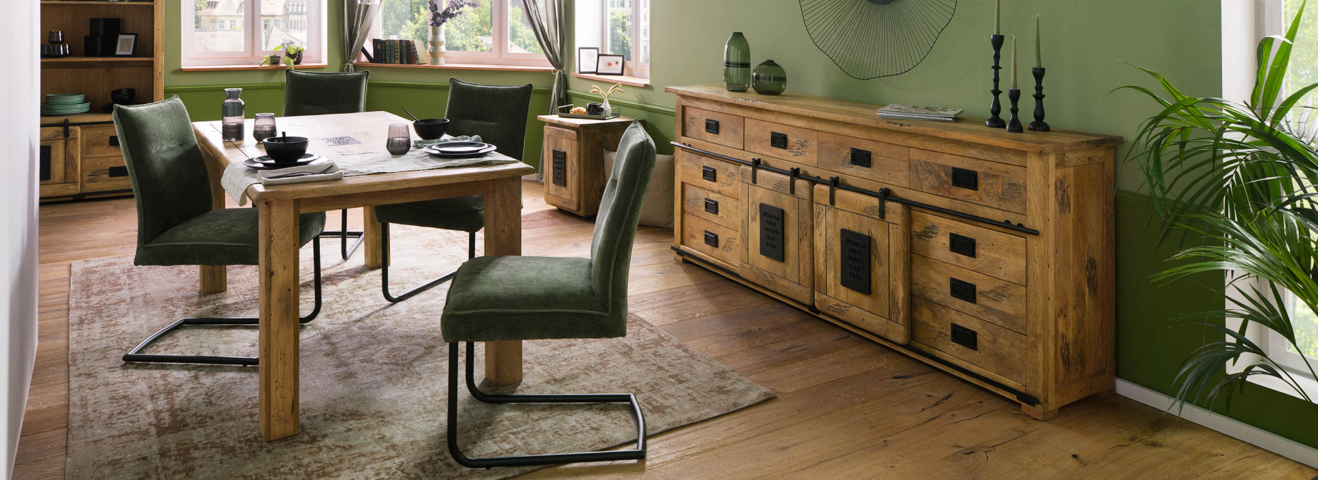 Stijlvolle RAILWAY-eetkamer in de kleur Nature, met een grote eettafel, groene stoelen en opvallende metalen details.