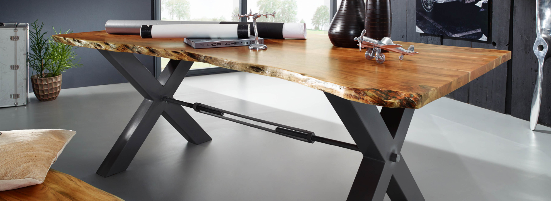 Massieve boomtafel met een lichtgekleurd houten blad, opvallende boomrand en een zwart metalen X-onderstel.