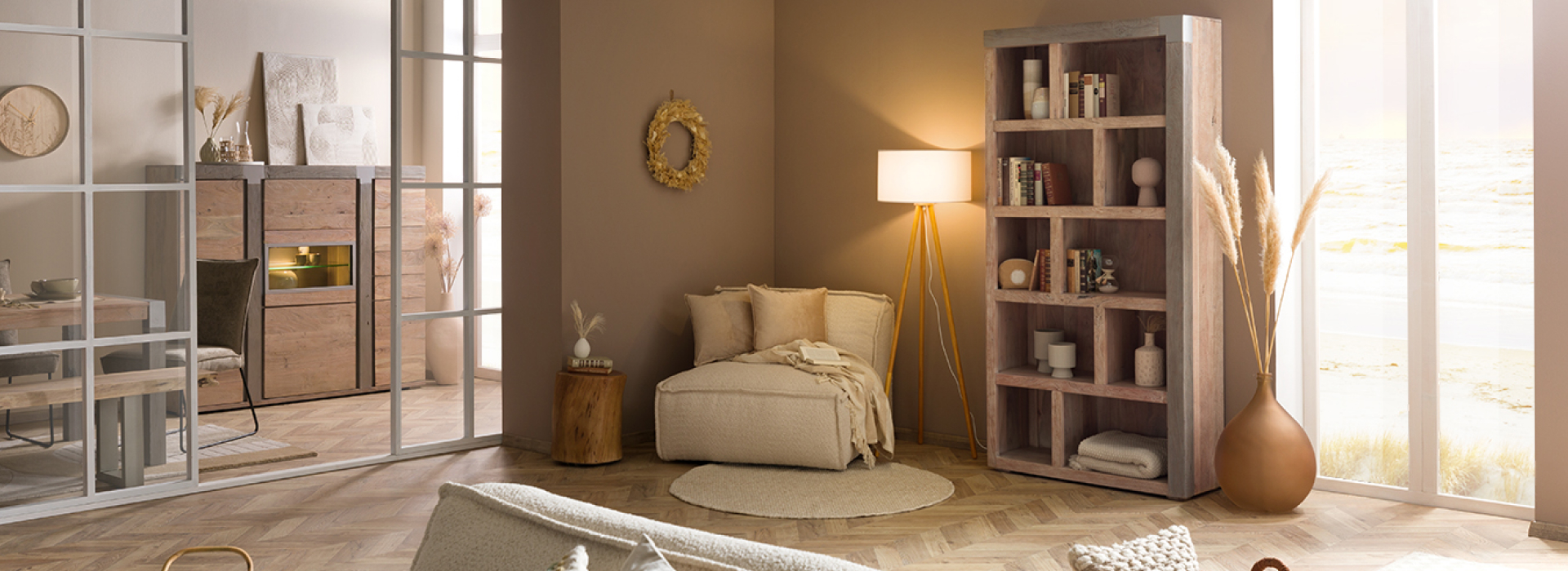 Moderne woon- en eetkamer uit de serie AMSTERDAM met wandmeubel, vitrinekasten, salontafel en open boekenkast in lichte houtlook en een crèmekleurige bank